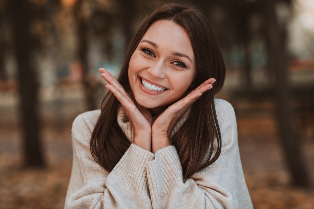 Happy woman with a beautiful smile framing her face, representing cosmetic dentistry results for patients in the Santa Cruz community 