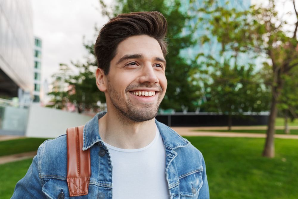 Young Man with Healthy Smile, General and Cosmetic Dental Care in Scotts Valley Young man with a confident, healthy smile outdoors in a park setting, representing dental patients served near Scotts Valley, CA